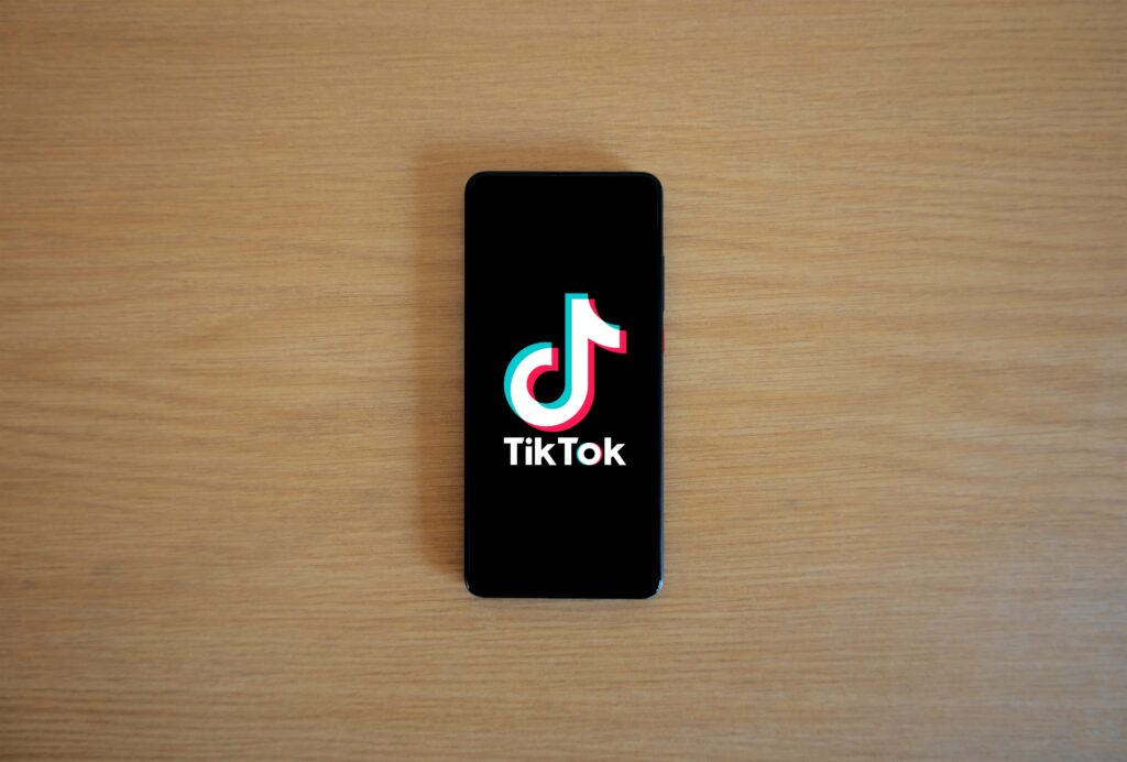 Smartphone with TikTok app displayed on black screen against a wooden background.